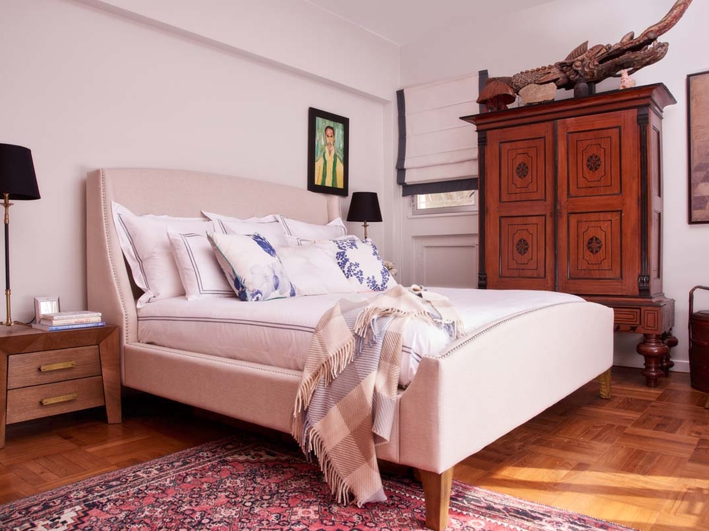 A huge upholstered bed serves as the focal point in John's master bedroom