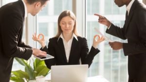 work stress - calm woman in office surrounded by angry colleagues