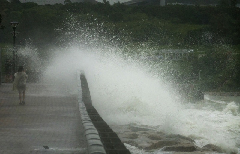 Image of woman walking near water during typhoon season